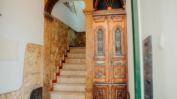 A staircase with stone walls and a wooden door with decorative glass panels. - Bright and Spacious Apt on the City Centre (Lisboa)