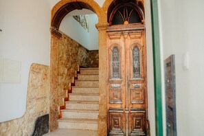 A staircase with stone walls and a wooden door with decorative glass panels. - Bright and Spacious Apt on the City Centre (Lisboa)