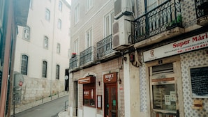 A narrow street with buildings featuring traditional architecture, including a restaurant named "Super Mário" with a visible phone number. - Bright and Spacious Apt on the City Centre (Lisboa)