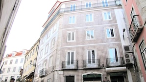 A multi-story building with a patterned facade, a ground-floor entrance with a sign, and a visible air conditioning unit. - Bright and Spacious Apt on the City Centre (Lisboa)
