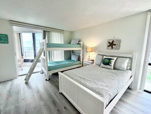 Une chambre avec des lits superposés, une table de chevet avec une lampe, une décoration en forme d’étoile de mer et une vue sur l’extérieur.