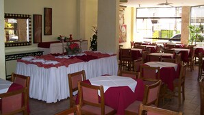 A restaurant with multiple tables and chairs, a large window, and ceiling fans. - Crystal Apart Hotel (Macaé)