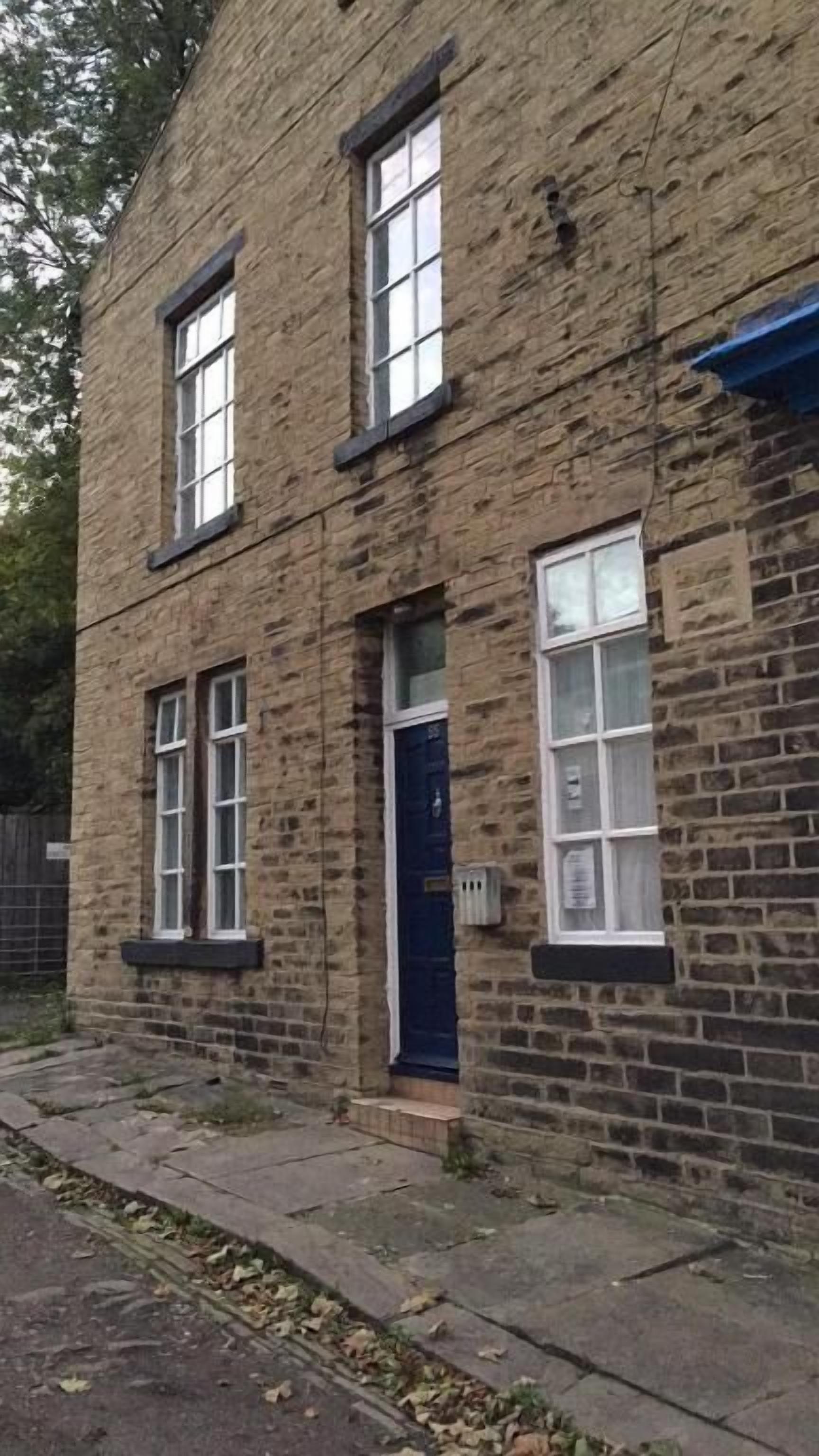 A two-story stone building with a blue door and windows.