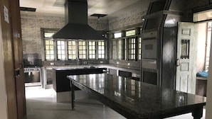 A spacious kitchen with a large island, built-in oven, and a range hood. - Skina Comfort - Stays & Events - Large House with Pool! (Guarujá)