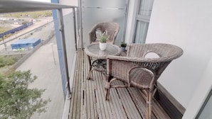 A balcony with wicker furniture and potted plants. - MK Hub Apartment with Oak Furniture (Milton Keynes)