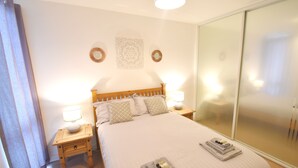 A neatly arranged bedroom with a bed, two bedside tables with lamps, a wardrobe, and decorative wall art. - MK Hub Apartment with Oak Furniture (Milton Keynes)