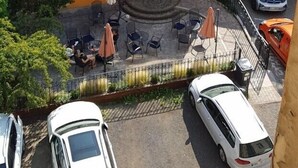 Un patio con mesas al aire libre, una zona techada y un coche estacionado al frente.