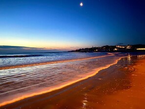 A beach at dusk with calm waves and a crescent moon in the sky. - Moody Maine Beautiful 3 Bedroom Home Walk to Beach Restaurants & Trolley Line (Wells)