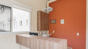 A modern kitchen with a wooden countertop, a window, and an orange wall. - OYO Hotel Jardim Emilia (Sorocaba)