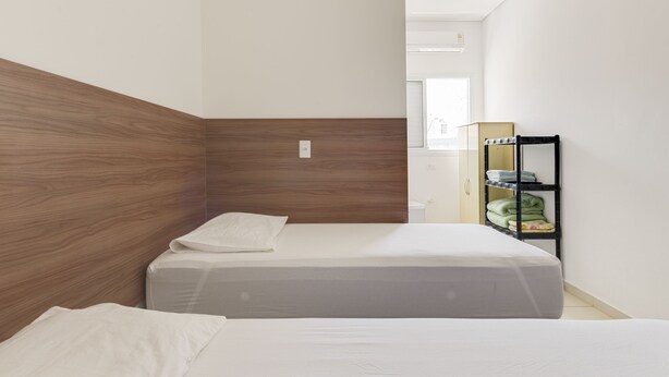 A bedroom with two beds, a wardrobe, and a window. - OYO Hotel Jardim Emilia (Sorocaba)
