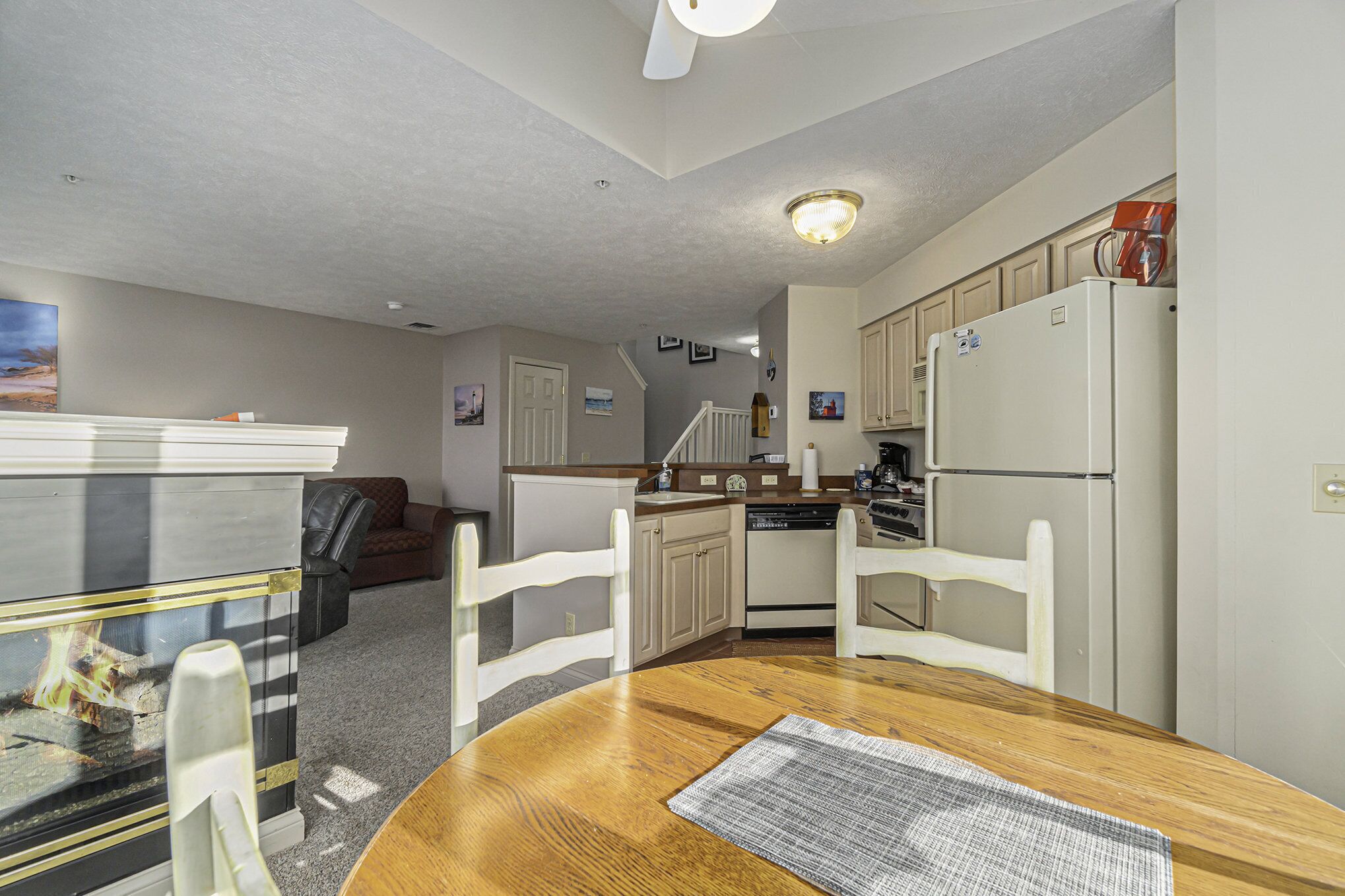 A compact kitchen with white cabinets, a refrigerator, and a dining area with a wooden table and chairs.