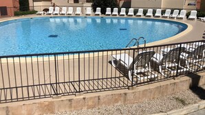 En swimmingpool med solstolar och ett staket.