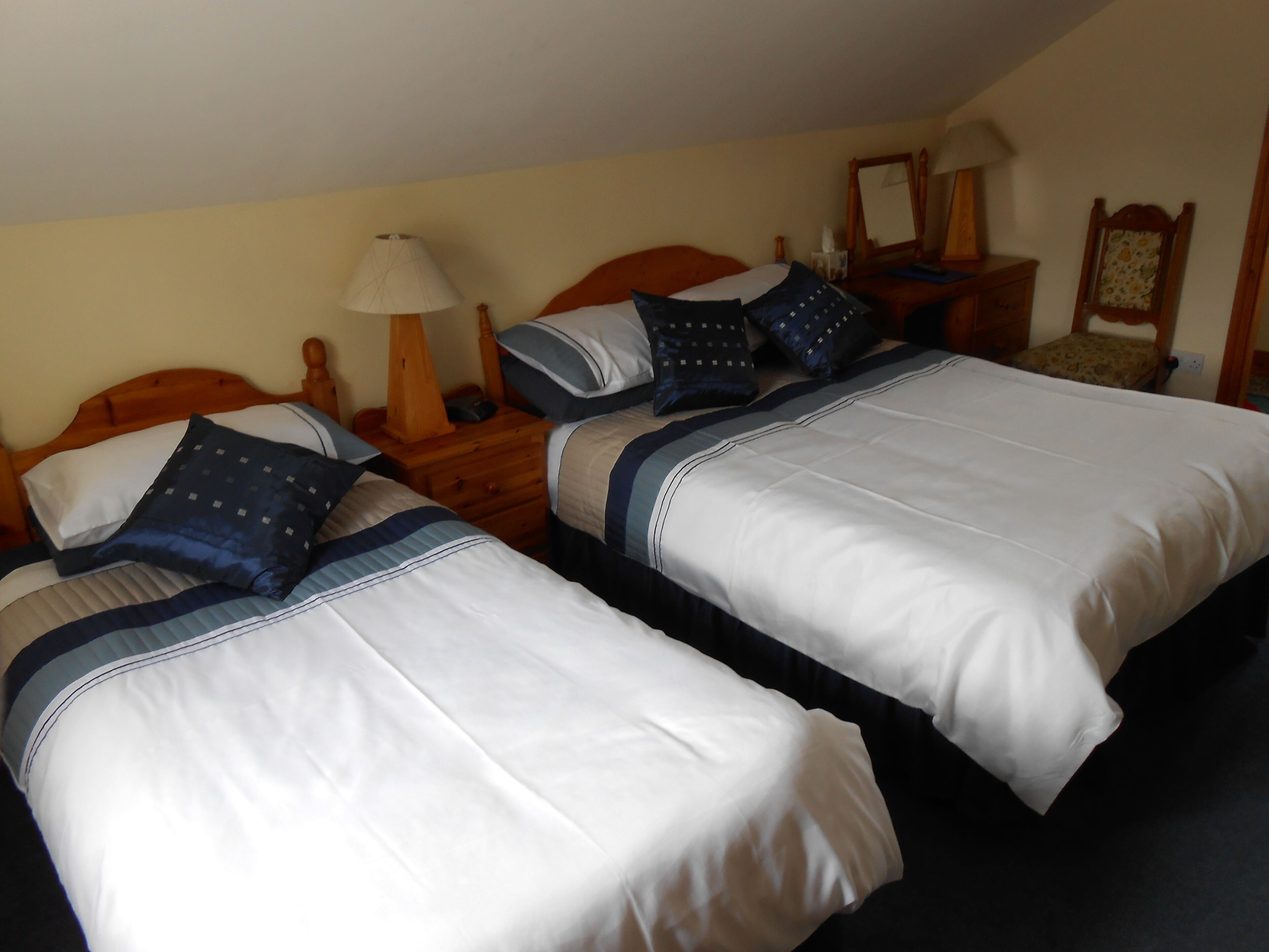 Two single beds with white and blue bedding, wooden headboards, and bedside tables with lamps.