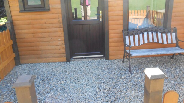 A wooden cabin with a black door, a bench, and a small table. - Birchdale House B&B (Greenan)