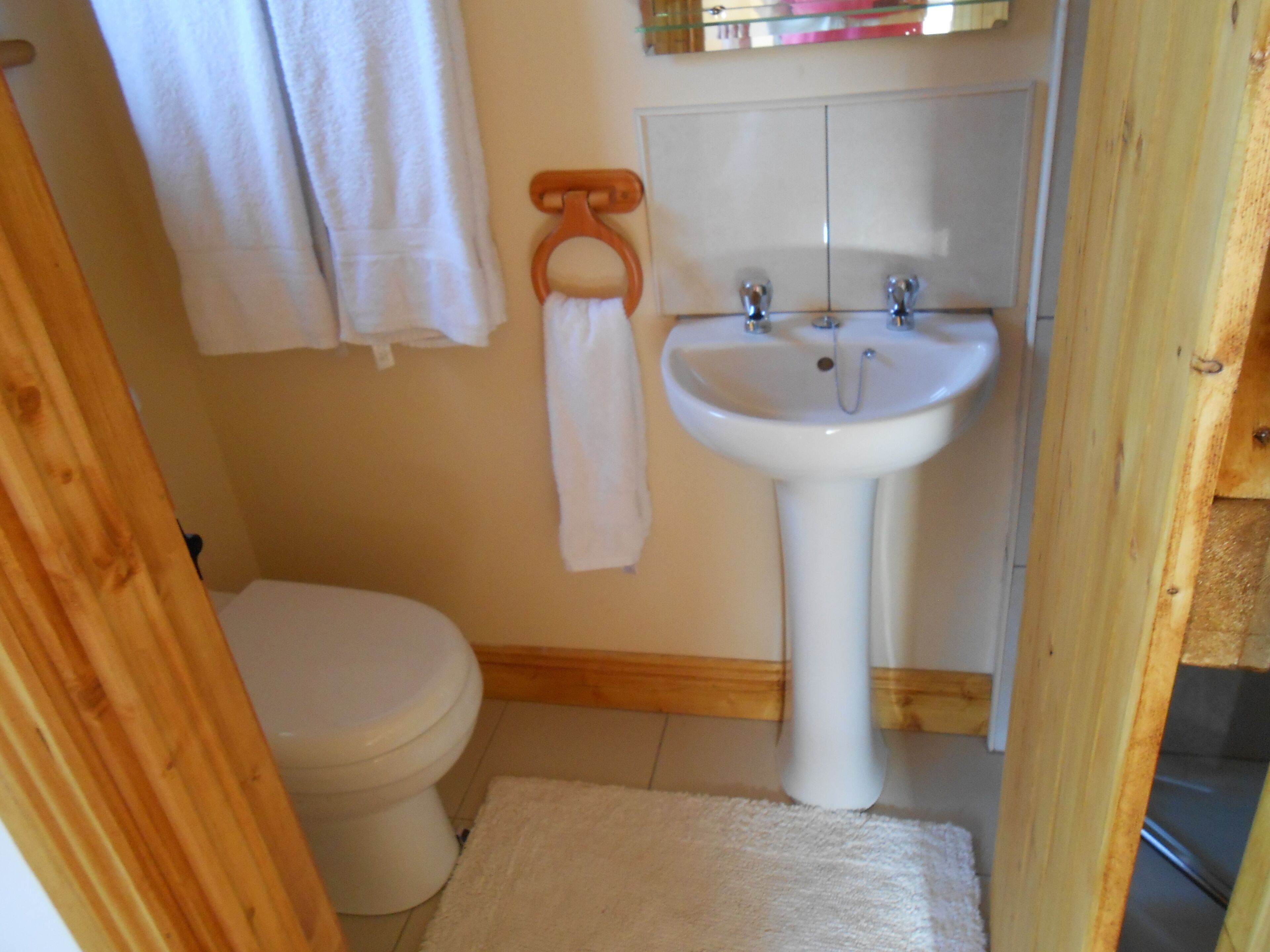 Un baño con lavamanos blanco, inodoro y marco de puerta de madera.