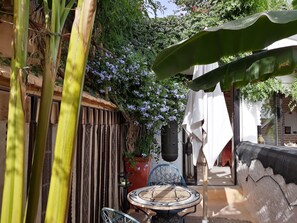 A patio with a table and chairs, surrounded by plants and a hanging plant. - Dar Oulhoum (Marrakech)