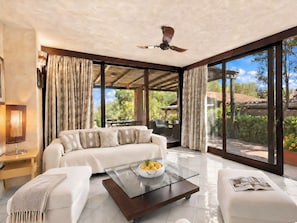 A modern living room with a sofa, a glass coffee table, and a ceiling fan.