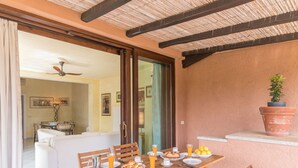 Un'area pranzo con un tavolo di legno apparecchiato per la colazione, inclusi piatti, tazze e una brocca di succo d'arancia.