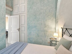 A bedroom with a bed, bedside table, lamp, and a wardrobe.