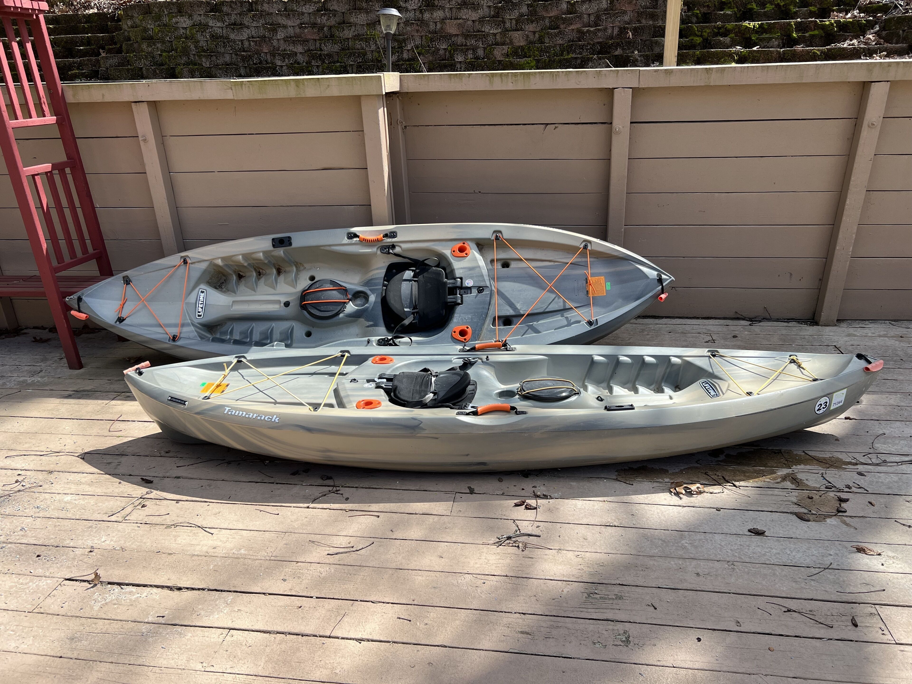 Dos kayaks con equipo de seguridad y una escalera, sobre una cubierta de madera.