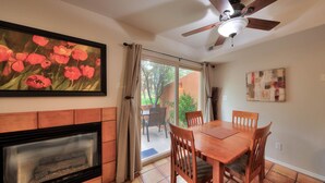A dining area with a wooden table and chairs, a fireplace, and a ceiling fan. - Stunning Moab townhome on the golf course! (Moab)