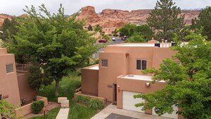 A residential area with stucco houses, green lawns, and a mountain backdrop. - Stunning Moab townhome on the golf course! (Moab)