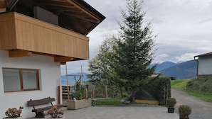 A modern house with a wooden balcony, a paved driveway, and a car parked in front. - Apartment #1 in Haus Sophia with a unique view (DG) (Oberperfuss)
