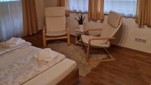 A cozy room with a bed, two chairs, a small table with a plant, and large windows with curtains. - Apartment #1 in Haus Sophia with a unique view (DG) (Oberperfuss)