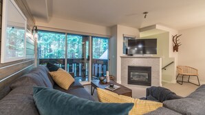 A modern living room with a fireplace, a sofa, a coffee table, and a television.