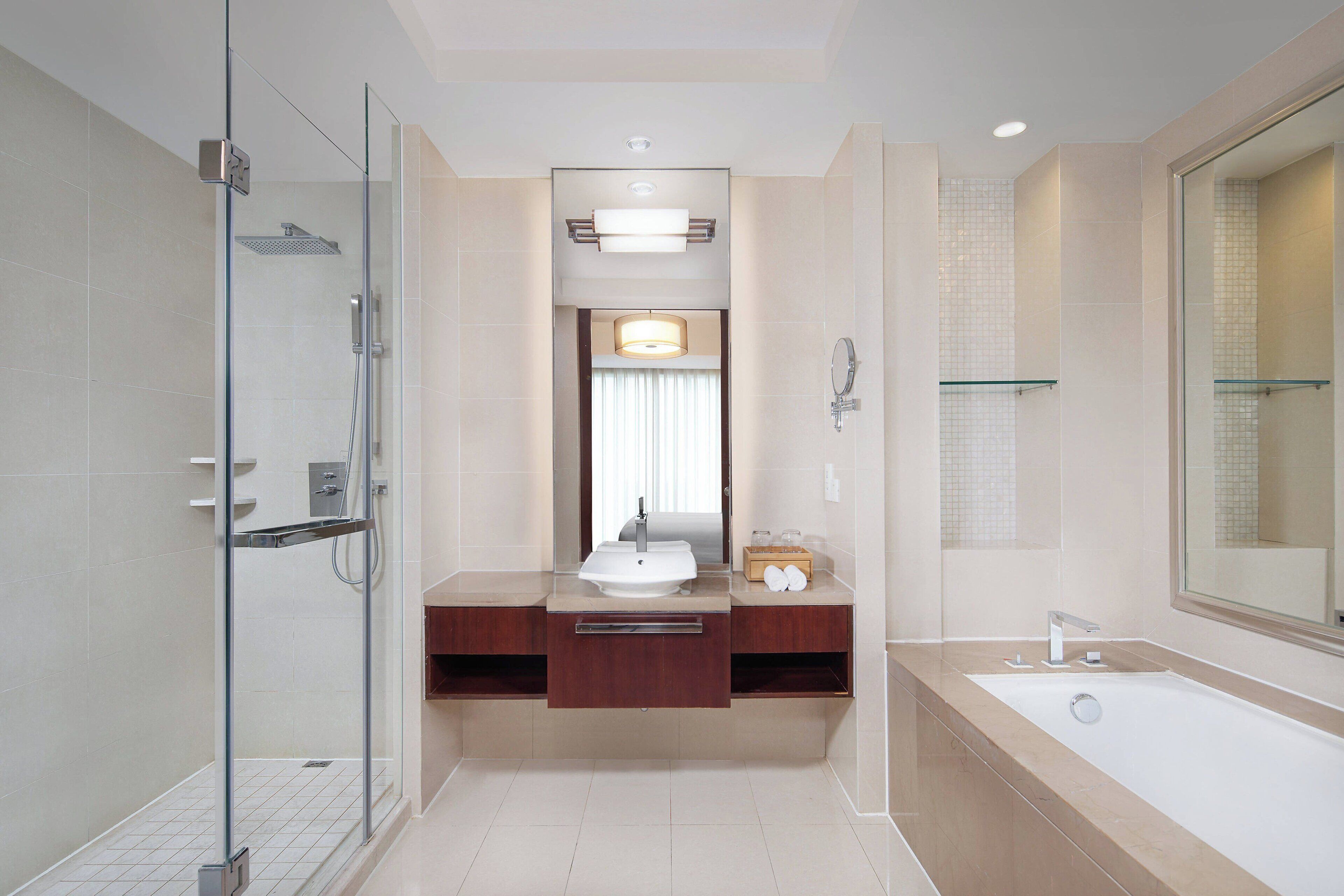 A modern bathroom with a glass shower enclosure, a large bathtub, and a vanity with a mirror.