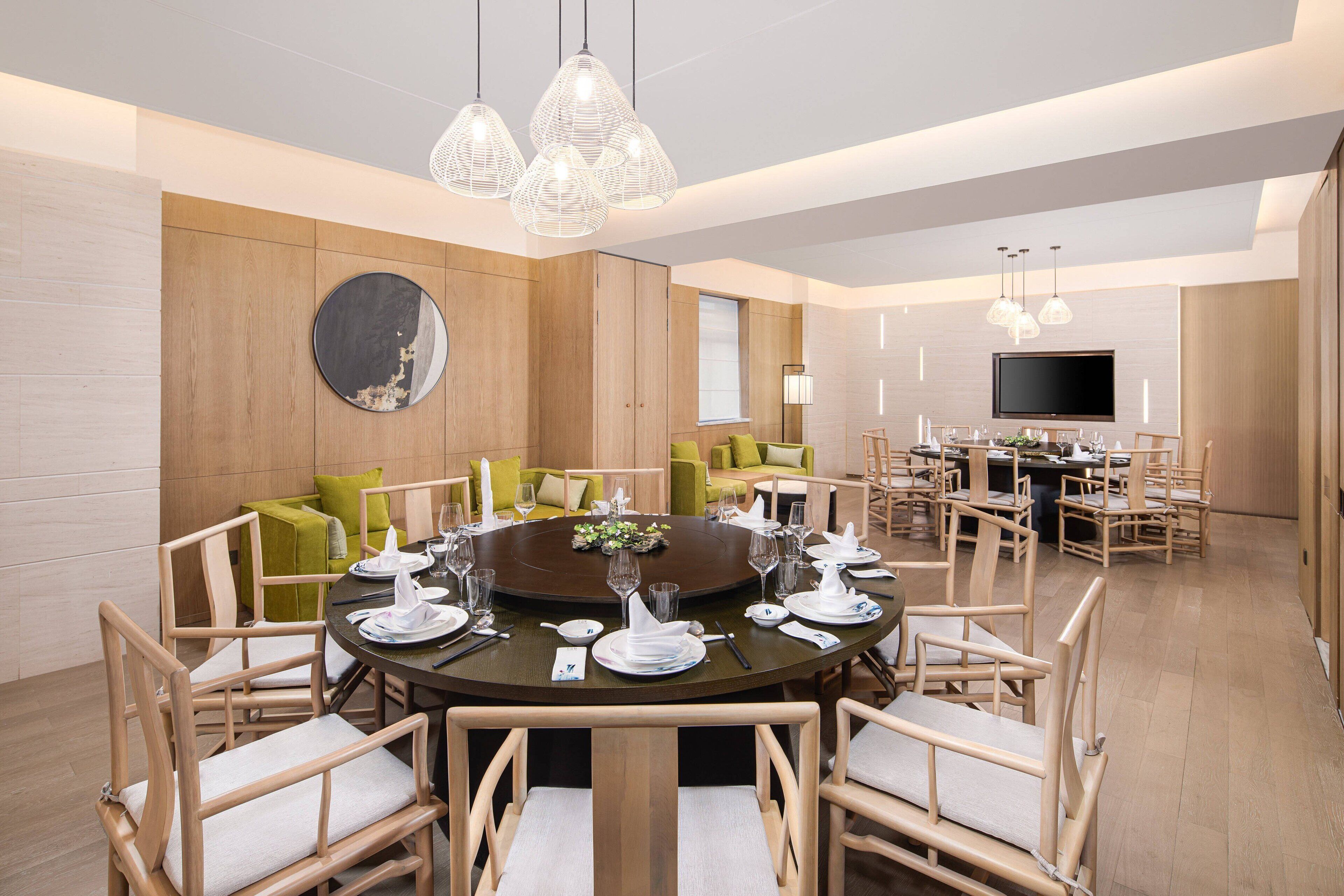 A modern dining area with a round table set for a meal, surrounded by wooden chairs.