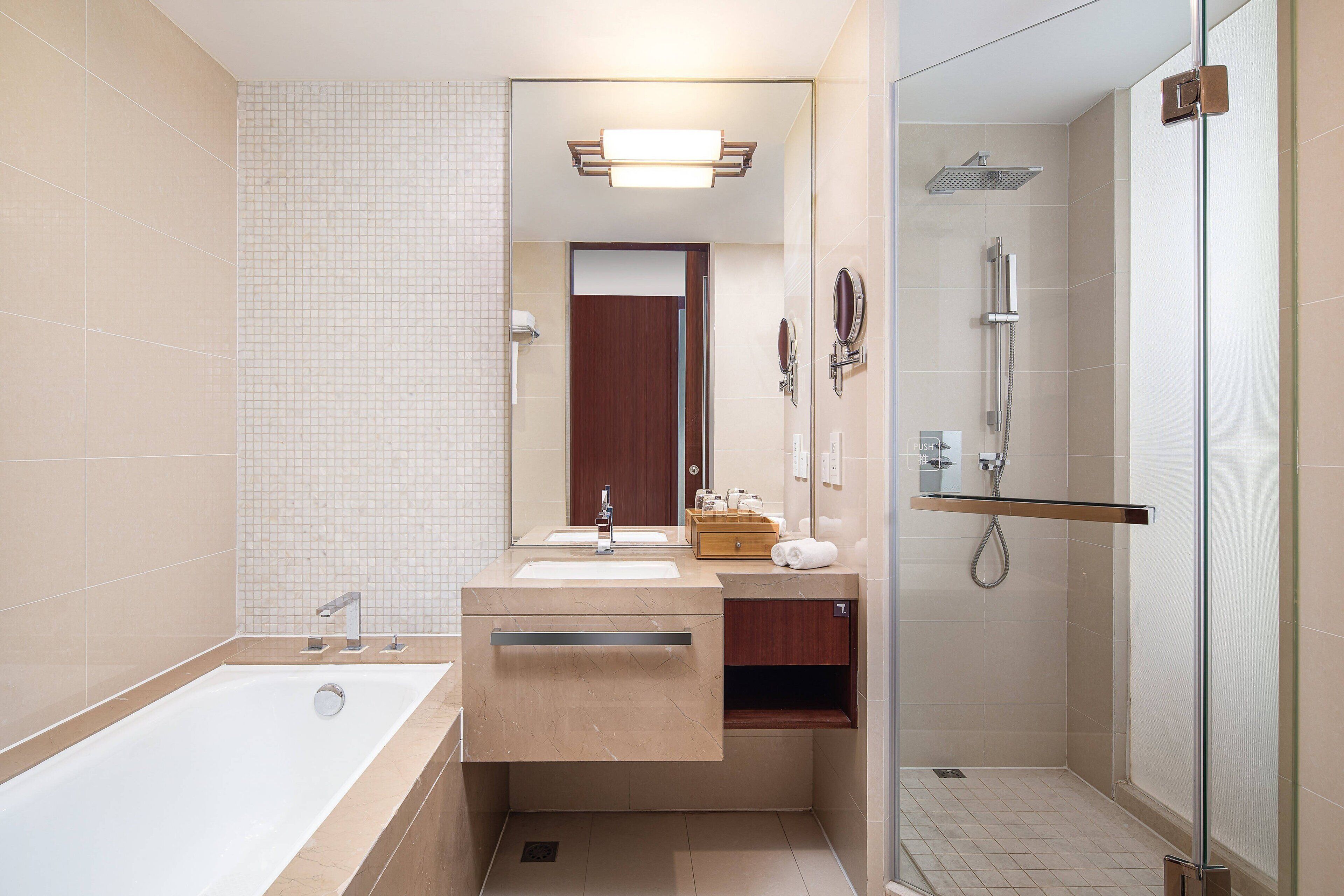 Ein modernes Badezimmer mit einer Badewanne, zwei Waschbecken, einer Duschkabine und einem Waschtisch inklusive Spiegel und Handtuchhalter.