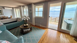 Un salon comprenant un canapé, une table basse avec un vase, et une vue sur l’océan grâce à de grandes portes-fenêtres coulissantes.