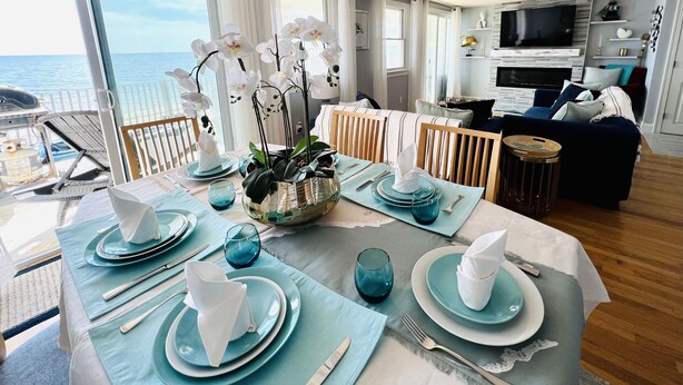 Un coin repas avec vue sur la mer, un salon équipé d’un téléviseur et un espace salon confortable.