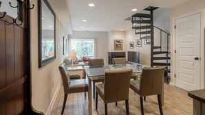 Un comedor con una mesa de vidrio y sillas, una escalera y una puerta.