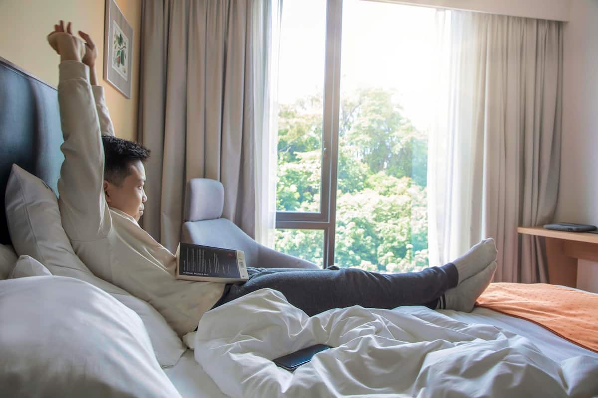 Ein Hotelzimmer mit Bett, einem fensterbelaubten Fenster und Blick auf Grün.