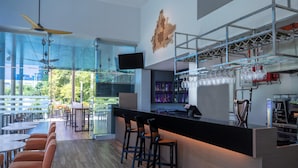 A modern bar area with a long counter, bar stools, and a television mounted on the wall. - Holiday Inn Express Kota Kinabalu City Centre by IHG (Kota Kinabalu)