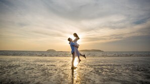 A beach scene with a couple embracing, a clear sky, and calm sea. - Holiday Inn Express Kota Kinabalu City Centre by IHG (Kota Kinabalu)