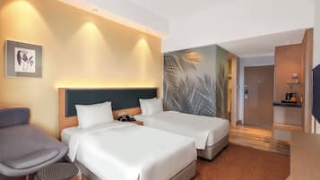 A hotel room with two beds, a desk, a chair, and a small round table.