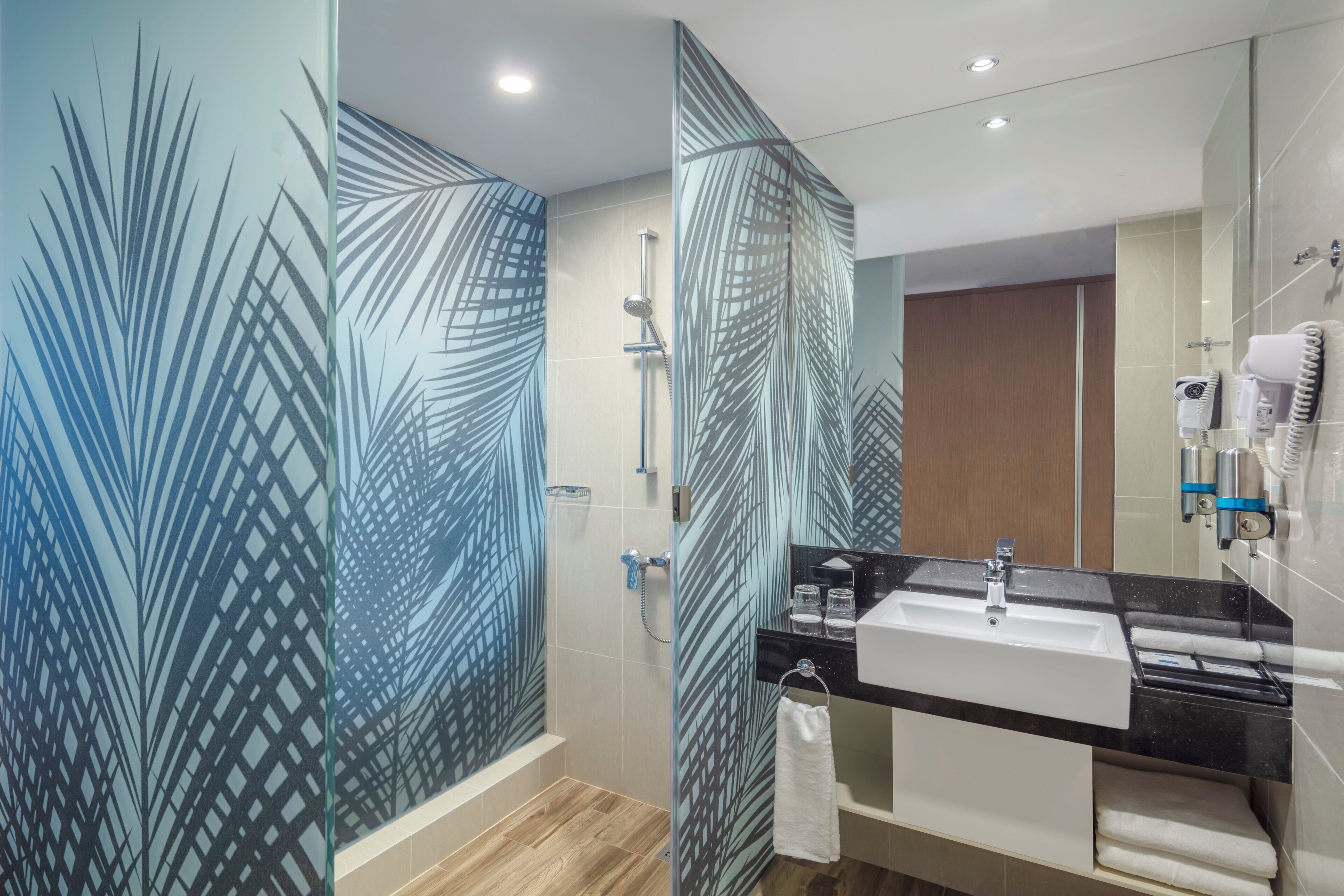 A modern bathroom with a glass shower enclosure, a black countertop sink, and a towel rack.