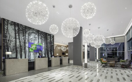 Un vestíbulo moderno de hotel con mostrador de recepción, grandes candelabros y una zona de estar.