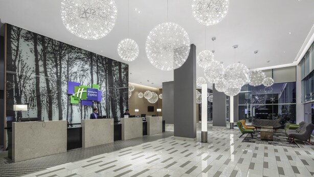 A modern hotel lobby with a reception desk, large chandeliers, and a seating area. - Holiday Inn Express Kota Kinabalu City Centre by IHG (Kota Kinabalu)
