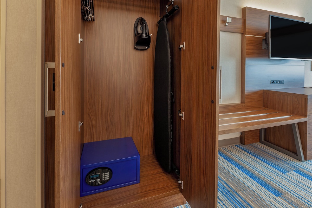 A compact room with a wooden door, a blue appliance, a black curtain, and a mounted TV.