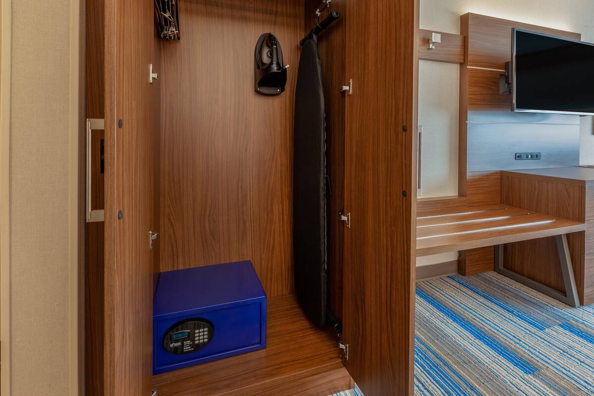 Una habitación compacta con una puerta de madera, un electrodoméstico azul, una cortina negra y un televisor montado.