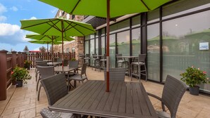 An outdoor patio area with wicker furniture, green umbrellas, and potted plants. - Holiday Inn Express & Suites Brunswick - Harpers Ferry Area by IHG (Knoxville)