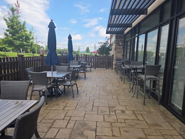 An outdoor patio with stone flooring, wicker furniture, and umbrellas.