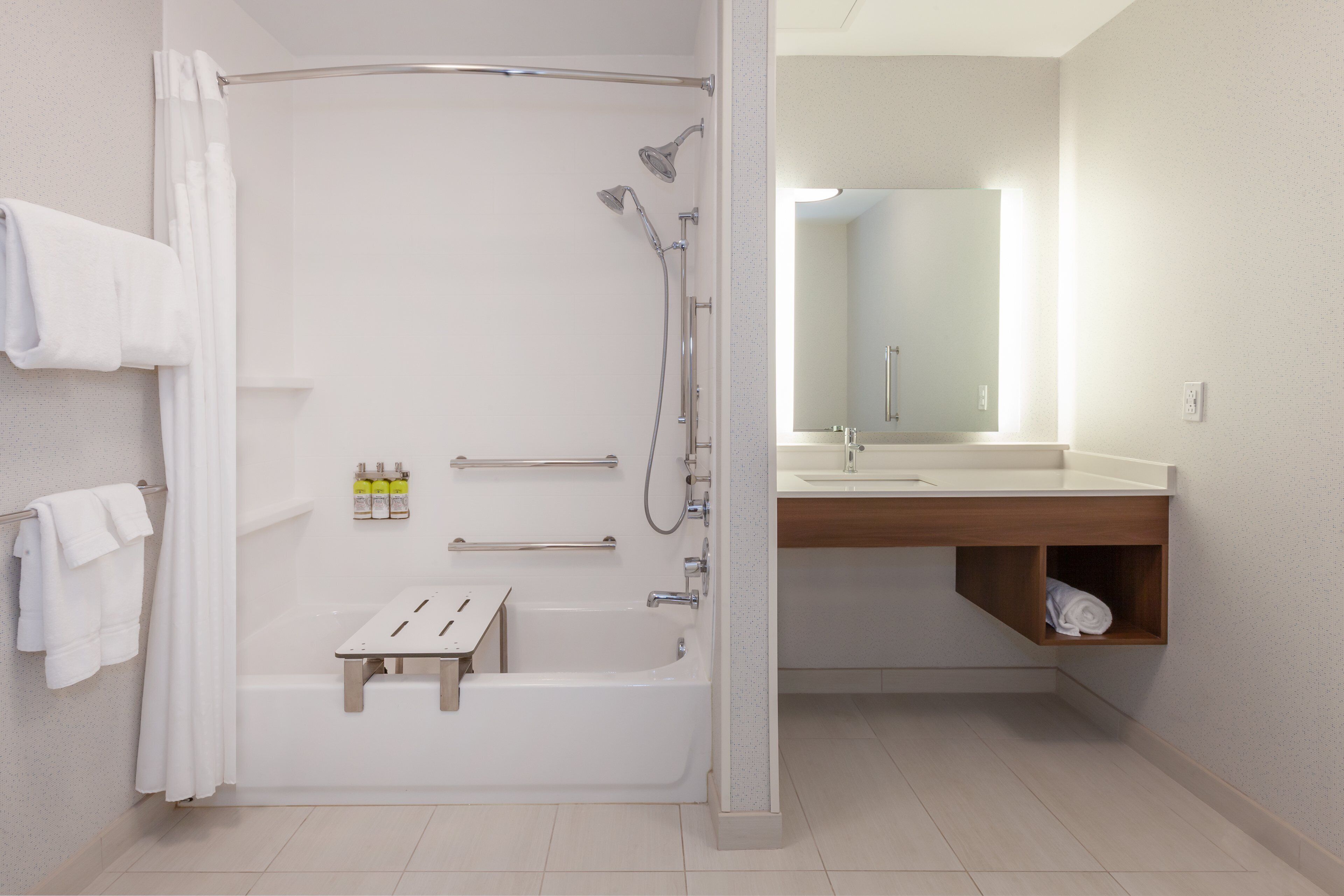 Un baño moderno con cabina de ducha, tocador de madera y espejo sobre el lavabo.