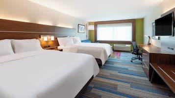 A hotel room with two beds, a desk, a television, and a window with blinds.