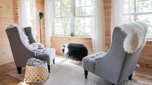 Une pièce chaleureuse avec deux fauteuils gris, un plaid blanc moelleux, un tapis noir à poils longs et un panier en osier.