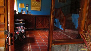 Ein rustikales Interieur mit Fliesenboden, Holzbalken, einer Treppe und einem Schild mit der Aufschrift 'La Roca de la Patagonia'.